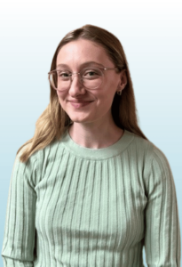 Smiling adult with long dark blond hair and glasses looks at the camera